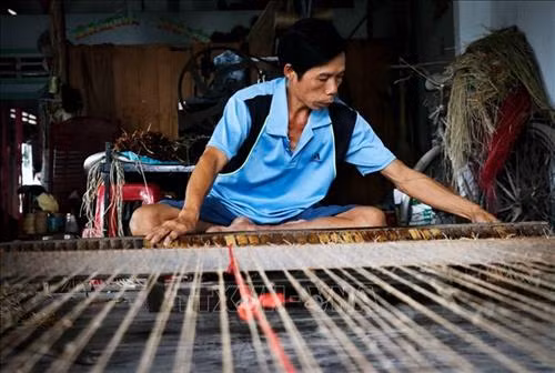 Nhiều hộ dân vẫn giữ phương pháp dệt chiếu thủ công bằng tay. Ảnh: Nam Thái - TTXVN