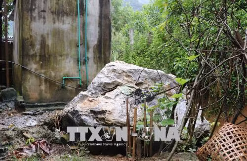 Một tảng đá kích thước hơn 4m3 đã lở và lăn từ vách núi đá phía sau bản xuống một hộ dân trong bản. Rất may, vị trí tảng đá lăn lệch nhà người dân đang sinh sống. Ảnh: Xuân Tiến-TTXVN