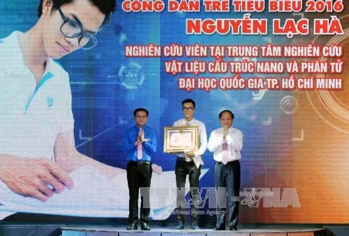 Phó Bí thư Thường trực Thành ủy Thành phố Hồ Chí Minh Tất Thành Cang trao bằng khen và biểu trưng cho nghiên cứu viên Nguyễn Lạc Hà tại Trung tâm Nghiên cứu vật liệu cấu trúc Nano và phân tử Trường Đại học Quốc gia TP Hồ Chí Minh. Ảnh: An Hiếu - TTXVN