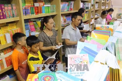 Phụ huynh tìm mua sách giáo khoa năm học mới cho con tại Công ty Cổ phần sách và thiết bị trường học Nghệ An. Ảnh: Bích Huệ - TTXVN