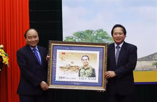 Bộ trưởng Bộ Thông tin và Truyền thông Trương Minh Tuấn thực hiện nghi thức trao tặng bộ tem cho Thủ tướng Nguyễn Xuân Phúc. Ảnh: Thống Nhất-TTXVN