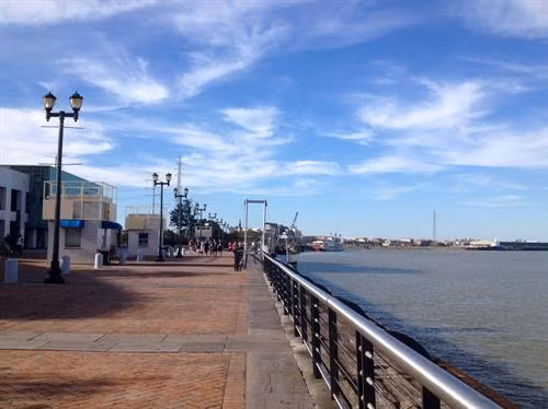 Con đường lát gạch dọc bờ sông. Quán cà phê ngoài trời trông ra phía con tàu hơi nước cổ.