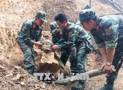 Các Chiến sĩ tiến hành tháo gỡ quả quả bom. Ảnh: Xuân Tư – TTXVN