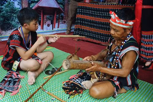 Nghệ nhân Bh’ling Argưnl (bên phải) truyền dạy đàn Gơrưna cho lớp trẻ Cơ Tu.