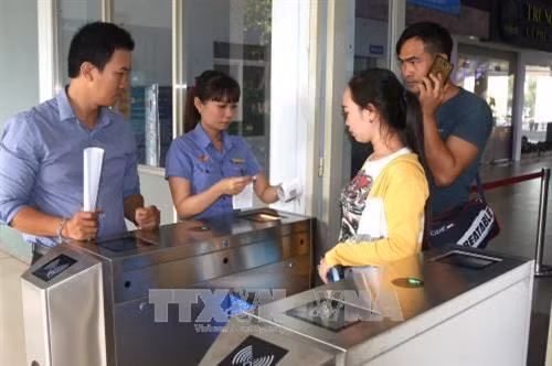 Hướng dẫn hành khách tại cổng soát vé tự động. Ảnh: Trần Xuân Tình-TTXVN