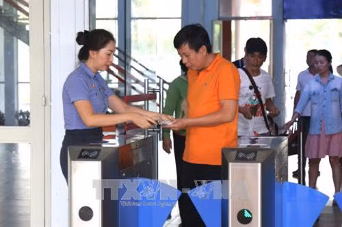 Hướng dẫn hành khách tại cổng soát vé tự động. Ảnh: Trần Xuân Tình-TTXVN