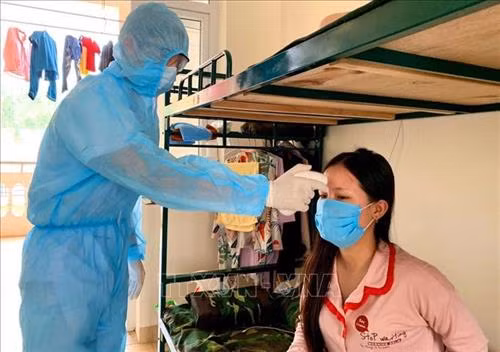 Cán bộ tổ công tác đo thân nhiệt cho người dân trong khu cách ly trường quân sự Sơn Tây. Ảnh: TTXVN phát