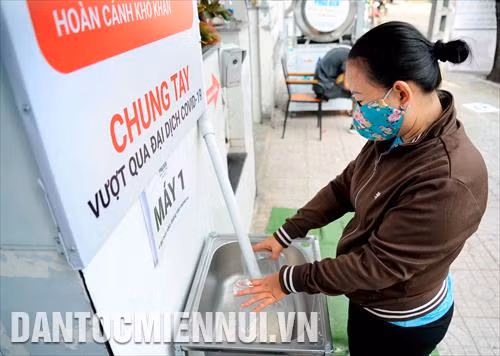 Người lao động nghèo đến nhận gạo chảy ra từ ống nhựa kết nối với thùng gạo được vận hành với công nghệ bán tự động