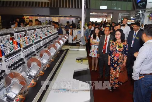 Khách tham quan khu trưng bày máy may công nghiệp, máy in, thêu tại triển lãm. Ảnh: Mạnh Linh-TTXVN