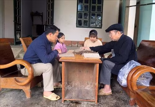 Ông Chu Tuần Ngân nghiên cứu, dạy lại chữ Nôm - Dao cho học trò và các cháu trong gia đình. Ảnh: Quang Đán - TTXVN