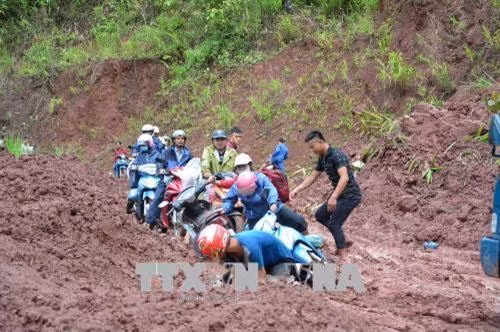 Người và phương tiện giao thông qua lại rất khó khăn tại điểm sạt lở. Ảnh: Văn Dũng –TTXVN