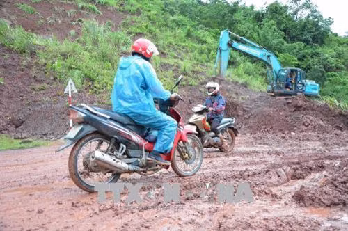 Người dân khó khăn khi đi qua điểm sạt lở. Ảnh: Văn Dũng –TTXVN