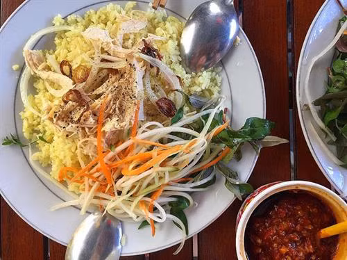 Cơm gà Tam Kỳ Bất cứ ai ghé thăm thành phố Tam Kỳ, tỉnh Quảng Nam đều phải thử món cơm ngon trứ danh này. Món ăn chỉ từ cơm và thịt gà nhưng cách chế biến cùng nguyên liệu đặc biệt của Tam Kỳ khó có thể so sánh với bất cứ địa danh nào khác. Nghệ thuật ẩm thực nơi đây đã cho ra đời món cơm gà đậm đà, hơi cay cay rất hấp dẫn với các món gà luộc, gà xé phay, gà sốt chua ngọt…