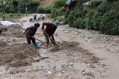 Nhân dân khắc phục đoạn đường bị sạt lở tại xã Pa Vây Sử. Ảnh: Quý Trung - TTXVN