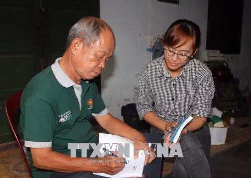 Nhà báo Trịnh Phi Long (trái) trao đổi kinh nghiệm nghề báo với phóng viên TTXVN. Ảnh: Xuân Khu-TTXVN
