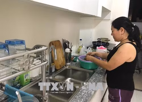 Chị Trần Thị Minh Thanh, cư dân bị ảnh hưởng trong vụ cháy chung cư Carina Plaza đang chuẩn bị buổi ăn cho gia đình trong căn hộ tạm cư chung cư City Gate Towers (đối diện chung cư Carina Plaza). Ảnh: Thanh Vũ - TTXVN