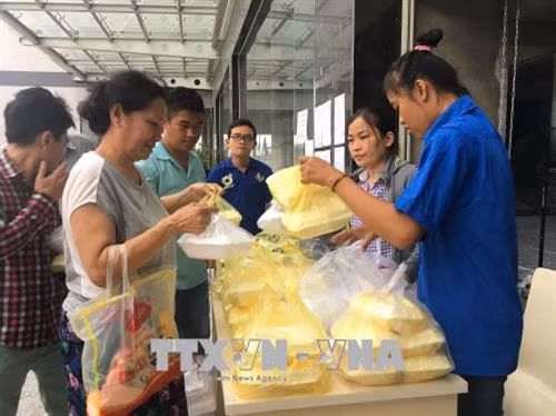 Cư dân chung cư Carina Plaza đang nhận suất ăn do các tổ chức, cá nhân hỗ trợ các gia đình bị ảnh hưởng trong vụ cháy tại sảnh chính của chung cư City Gate Towers (đối diện chung cư Carina Plaza). Ảnh: Thanh Vũ - TTXVN