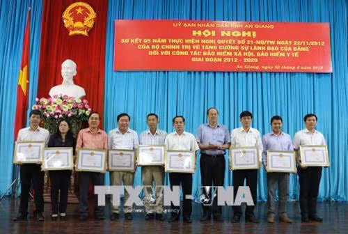 Phó Chủ tịch UBND tỉnh An Giang Nguyễn Thanh Bình trao bằng khen của UBND tỉnh cho các tập thể có thành tích xuất sắc trong tổ chức thực hiện chính sách BHXH, BHYT, Bảo hiểm thất nghiệp trên địa bàn tỉnh An Giang từ năm 2012-2017. Ảnh: Công Mạo - TTXVN