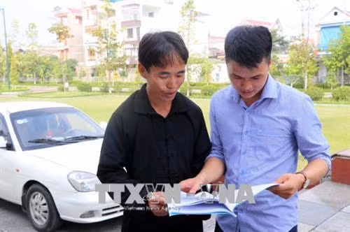 Anh Hoàng Văn Tài (bên trái), dân tộc Mông, Bí thư Chi bộ thôn Khuổi Phầy đang trao đổi kinh nghiệm dân vận. Ảnh: Quang Đán - TTXVN