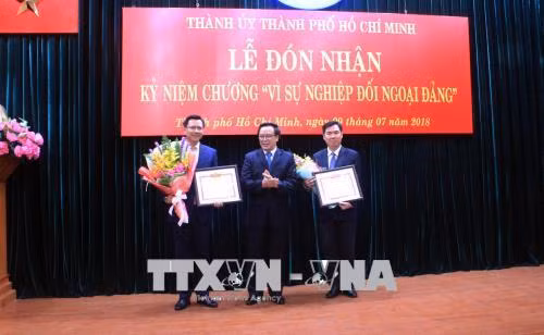 Đồng chí Hoàng Bình Quân, Ủy viên Trung ương Đảng, Trưởng ban Đối ngoại Trung ương (giữa) trao bằng khen cho đại diện Sở Ngoại vụ Thành phố và Văn phòng Thành ủy Thành phố. Ảnh: Xuân Khu-TTXVN