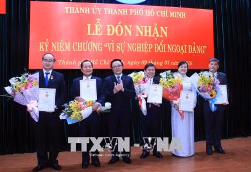 Đồng chí Hoàng Binh Quân, Ủy viên Trung ương Đảng, Trưởng ban Đối ngoại Trung ương (thứ 3 từ trái sang) trao kỷ niệm chương cho các đồng chí lãnh đạo, nguyên lãnh đạo Thành phố. Ảnh: Xuân Khu-TTXVN