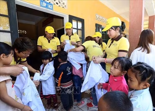 Các em học sinh mặc thử áo đồng phục được tặng. Ảnh: Phan Tuấn Anh - TTXVN