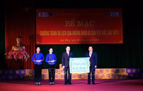 Đại diện lãnh đạo UBND tỉnh Cao Bằng trao cờ đăng cai tổ chức Chương trình du lịch "Qua những miền di sản Việt Bắc" lần thứ XI cho tỉnh Lạng Sơn. Ảnh: Chu Hiệu - TTXVN