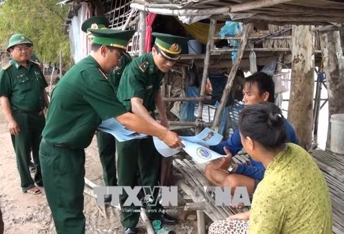 Bộ đội biên phòng Đồng Tháp tổ chức phát tờ rơi tuyên truyền về biển, đảo quê hương đến tận tay người dân vùng biên. Ảnh: Chương Đài - TTXVN