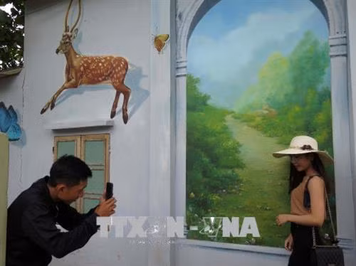 Du khách chụp ảnh tại làng Bích họa. Ảnh: TTXVN