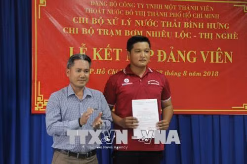 Trao quyết định kết nạp Đảng cho đoàn viên Lê Thanh Tuấn, công nhân bảo dưỡng máy của Nhà máy xử lý nước thải Bình Hưng, chiến sĩ tham gia chiến dịch tình nguyện Kỳ nghỉ hồng năm 2018. Ảnh: Xuân Dự - TTXVN