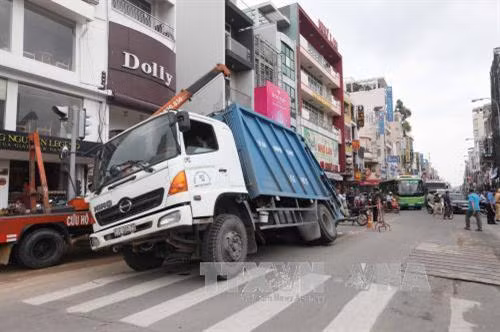 Chiếc xe chở rác sụp “hố tử thần”. Ảnh: Mạnh Linh-TTXVN