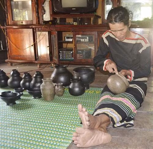 Nghệ nhân H'Lưm Uông đang tạo hoa văn cho nồi gốm.