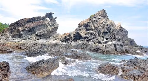 Ghềnh đá Bàn Than thuộc xã đảo Tam Hải, huyện Núi Thành, tỉnh Quảng Nam có những vỉa đá lớn màu đen lấp lánh với nhiều đường vân kỳ lạ trên mặt đá, đua ra hướng biển. Ảnh: Đỗ Trưởng - TTXVN