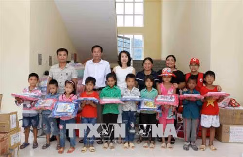 Bà Đặng Thị Loan, cùng các thành viên Câu lạc bộ những tấm lòng vàng hướng về Lai Châu trao Cặp sách, sách giáo khoa cùng vở viết cho học sinh trường Tiểu học PTDTBT Mù Cả, huyện Mường Tè. Ảnh: Quý Trung – TTXVN
