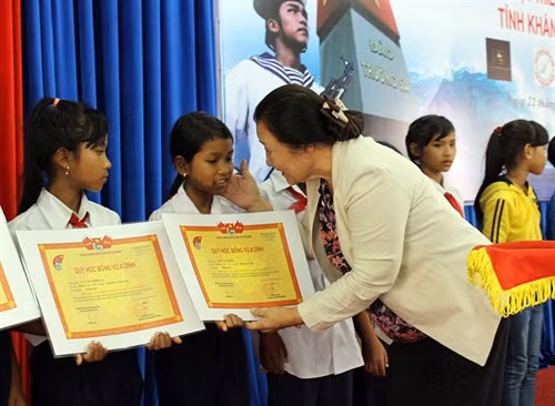 Đại diện quỹ học học bổng câu lạc bộ “ Vì Hoàng Sa, Trường Sa thân yêu” trao học bổng cho các em học sinh. Ảnh: Phan Sáu – TTXVN