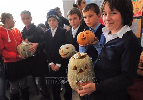 Các em học sinh giới thiệu các tác phẩm chạm khắc bí ngô chào đón Lễ Halloween ở Bucharest. Ảnh: AFP/TTXVN