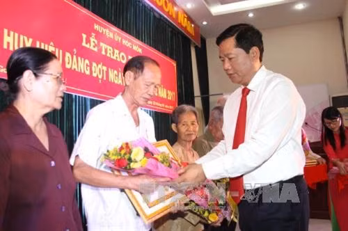 Đồng chí Đinh La Thăng, Ủy viên Bộ Chính trị, Bí thư Thành ủy Thành phố Hồ Chí Minh trao huy hiệu 70 năm tuổi đảng cho các đồng chí lão thành cách mạng. Ảnh: Thanh Vũ-TTXVN