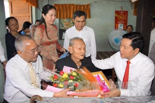 Đồng chí Đinh La Thăng, Bí thư Thành ủy Thành phố Hồ Chí Minh đến xã Thới Tam Thôn, huyện Hóc Môn trao huy hiệu 70 năm tuổi đảng cho đồng chí Nguyễn Văn Hoảnh (sinh năm 1928). Ảnh: Thanh Vũ-TTXVN