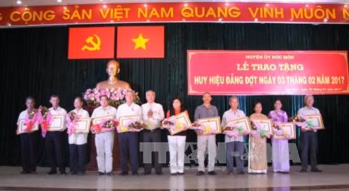 Đồng chí Nguyễn Cư, Bí thư Huyện ủy huyện Hóc Môn trao huy hiệu 65 năm tuổi đảng cho đồng chí lão thành cách mạng. Ảnh: Thanh Vũ-TTXVN