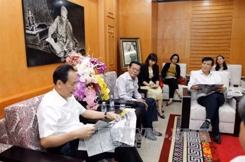 Xã trưởng Tân Hoa xã Thái Danh Chiếu xem ấn phẩm Báo Sài Gòn Giải Phóng bản tiếng Trung tại buổi tiếp. Ảnh: Hoàng Hải-TTXVN