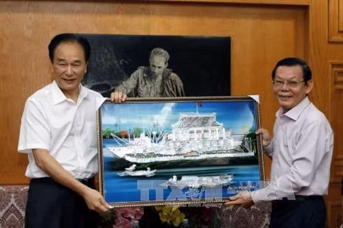 Tổng Biên tập báo Sài Gòn Giải Phóng Nguyễn Tấn Phong (phải) trao tặng bức tranh cho đồng chí Thái Danh Chiếu, Xã trưởng Tân Hoa xã tại buổi tiếp. Ảnh: Hoàng Hải-TTXVN