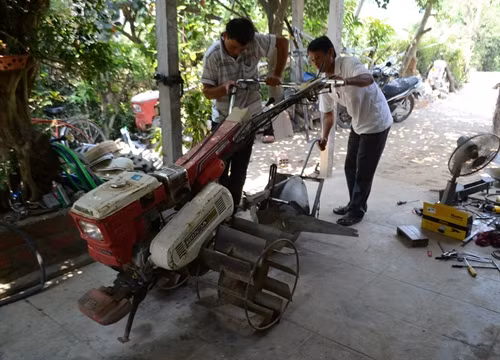 Ông Huỳnh Tiển (phải) cùng con trai chế tạo, lắp ráp máy lên luống.