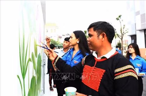 Anh Y Hlý Niê Kdăm tham gia vẽ tranh bích họa tại trường THCS Tứ Liên (Tây Hồ, Hà Nội). Ảnh: TTXVN