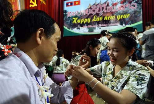 Nghi thức buộc chỉ cổ tay cầu may trong dịp tết cổ truyền Bunpimay. Ảnh: Phan Tuấn Anh - TTXVN