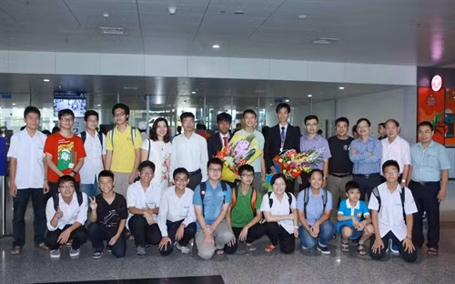 Người thân cùng thầy, cô giáo và các bạn tặng hoa chúc mừng Phạm Cao Nguyên và Phan Đức Nhật Minh giành Huy chương Vàng kỳ thi Olympic Tin học quốc tế lần thứ 28. Ảnh: Quý Trung - TTXVN
