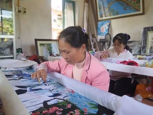 Nghệ nhân ưu tú Nguyễn Thị Hoan (người phía trước) miệt mài bên khung thêu. Ảnh: Mạnh Minh- TTXVN