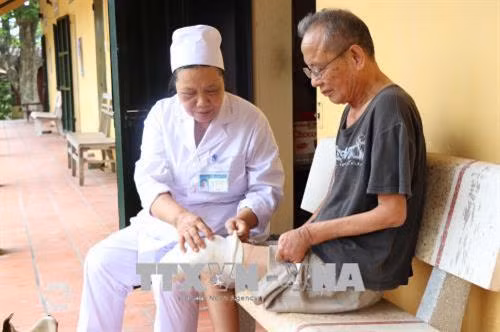 Y tá Nguyễn Thị Xuân kiểm tra khớp chân của bệnh nhân phong. Ảnh: Diệp Trương - TTXVN