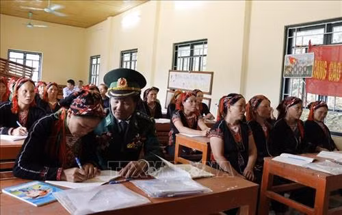 Cựu chiến binh Đỗ Minh Bản dạy đồng bào dân tộc thiểu số viết chữ. Ảnh: Đinh Thùy-TTXVN
