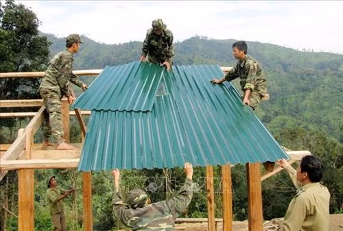 Cán bộ, chiến sỹ Bộ đội Biên phòng Lai Châu giúp dân dựng nhà, lập bản để định cư, ổn định cuộc sống. Ảnh: Công Tuyên-TTXVN