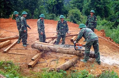 Cán bộ, chiến sỹ Bộ đội Biên phòng Lai Châu sẻ gỗ giúp dân dựng nhà. Ảnh: Công Tuyên-TTXVN